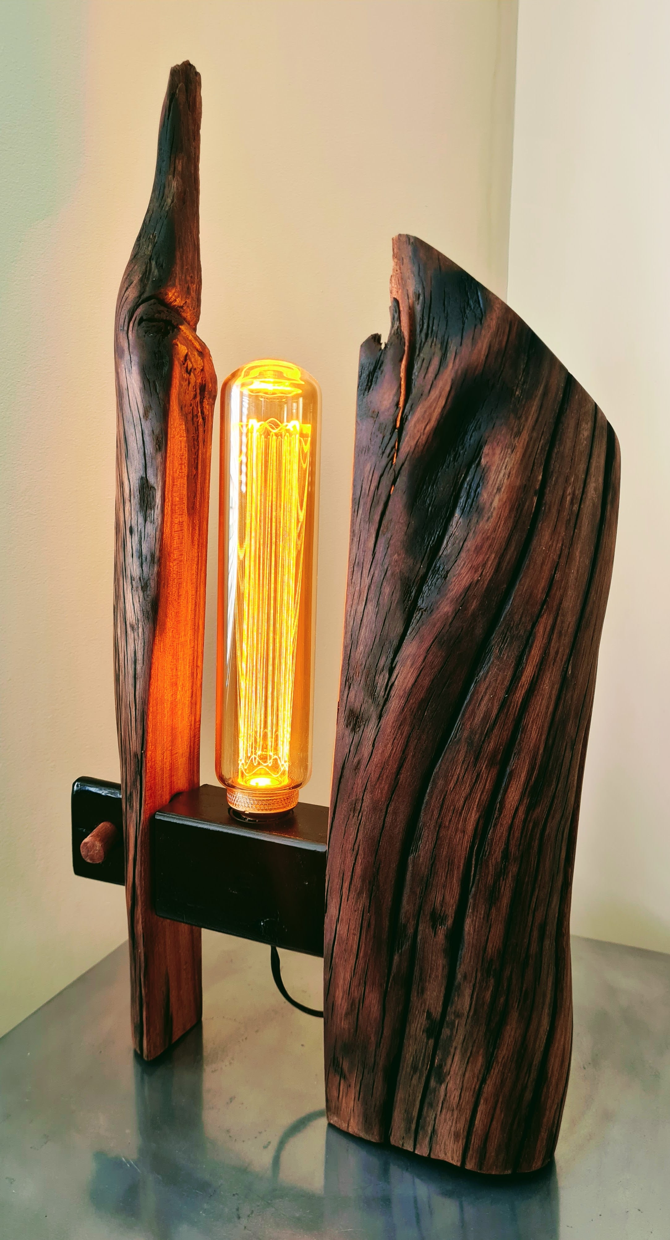 Wooden lamp with a glowing bulb on a reflective surface