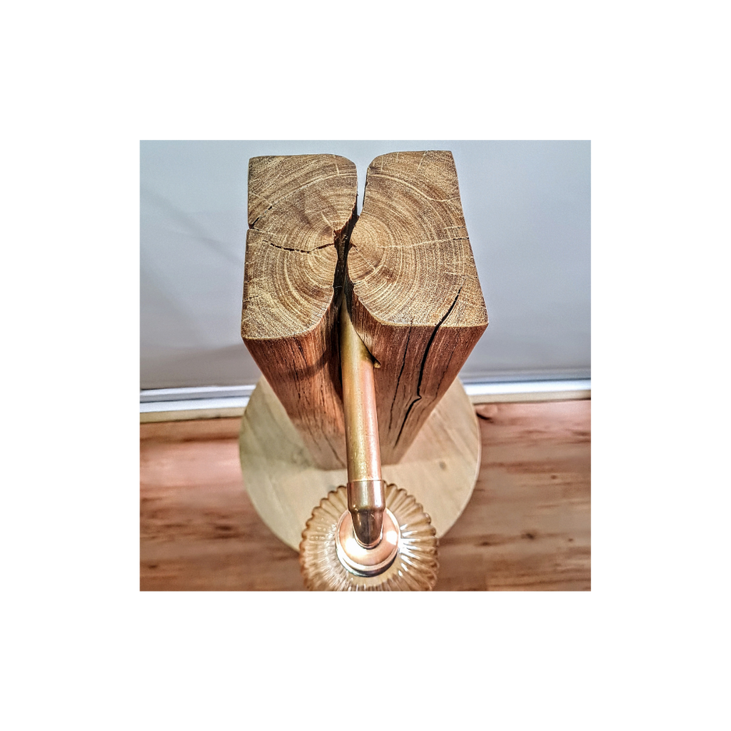 Wooden log with a metal pipe running through it on a wooden surface.