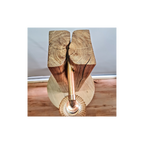 Wooden log with a metal pipe running through it on a wooden surface.