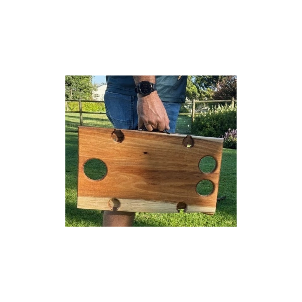 Person holding a wooden wine table outdoors on a grassy area.