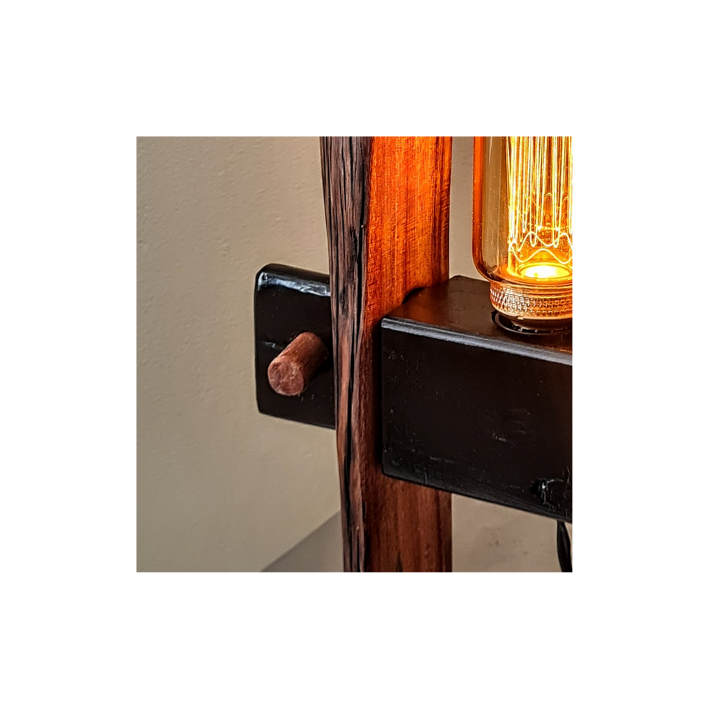 Wooden lamp with black brackets against a white wall.