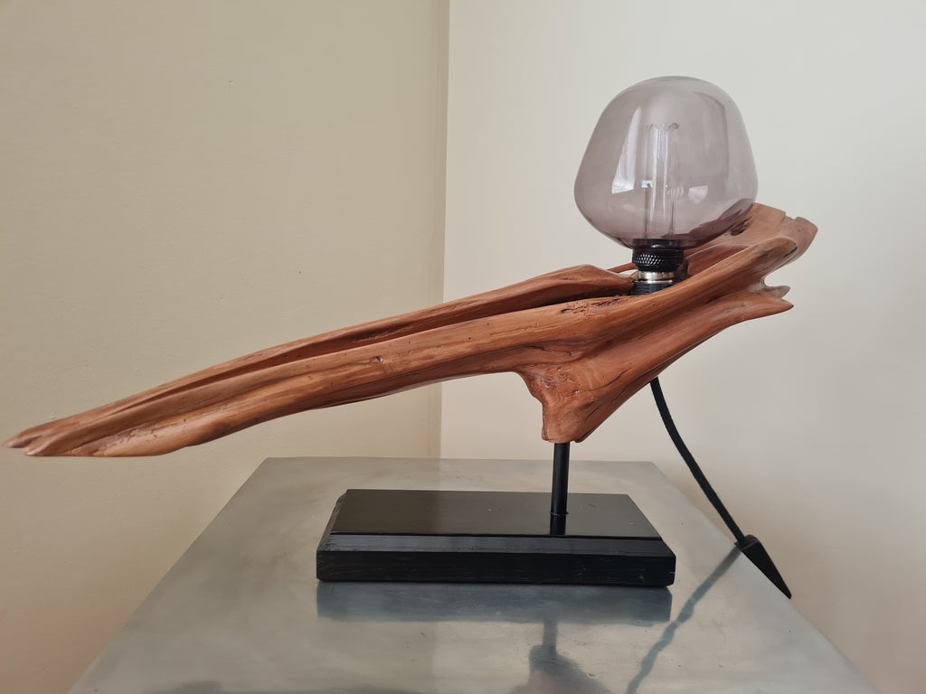 Wooden lamp with a glass shade on a reflective surface