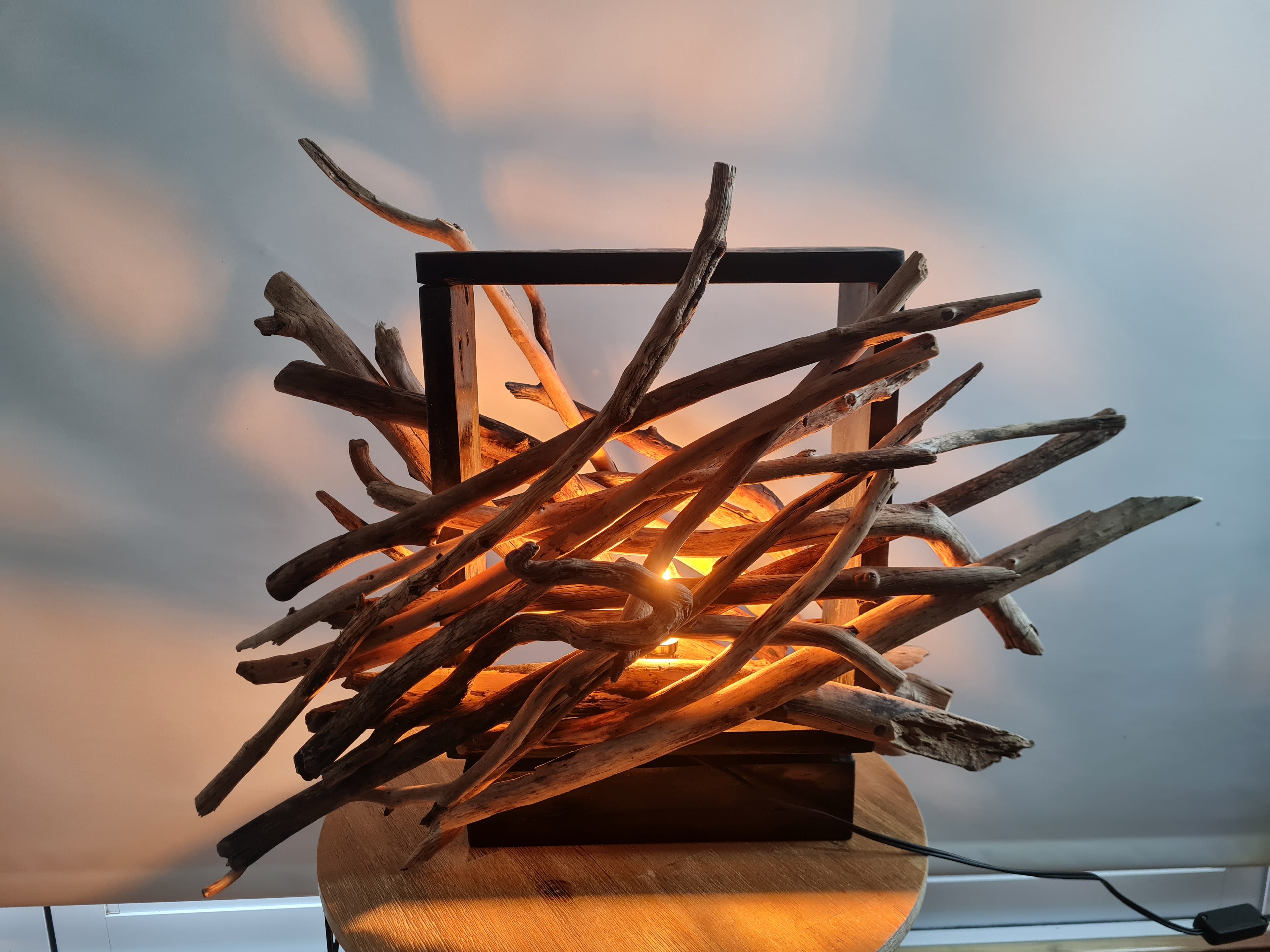Lamp made of interwoven branches with a warm glow against a neutral background
