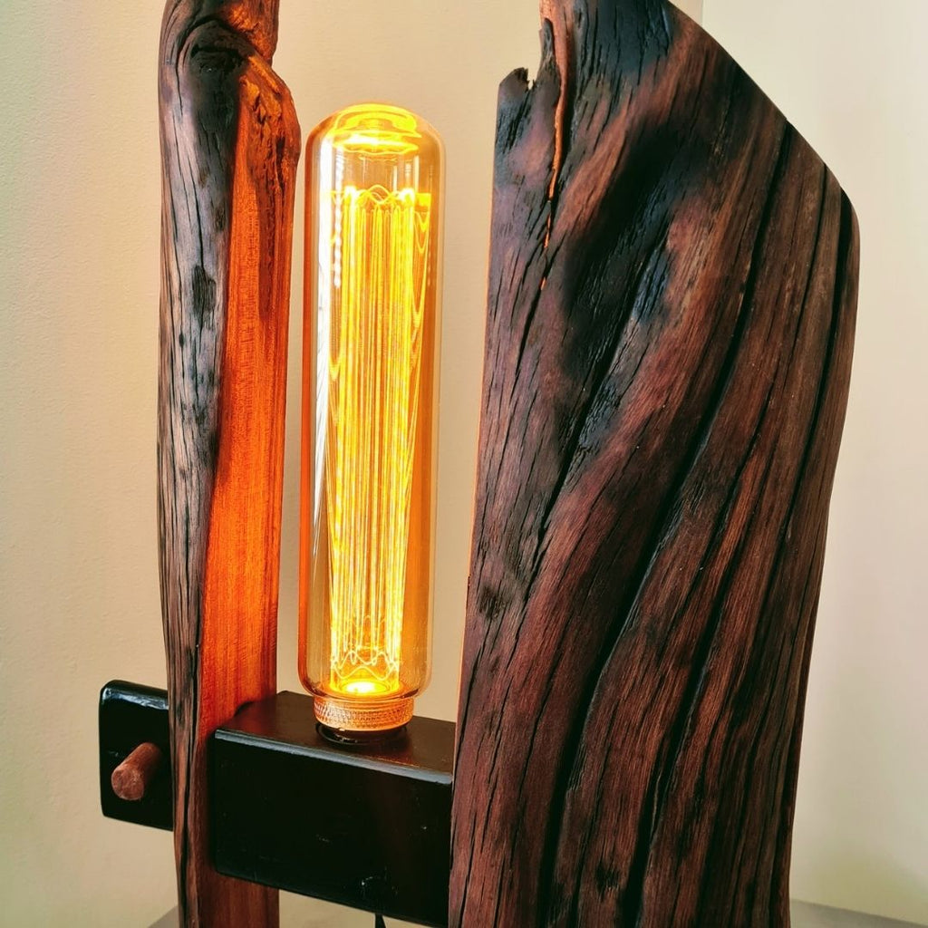 Wooden lamp with a glowing light bulb on a plain background